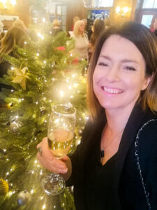 Sian with a glass of champagne next to a Christmas tress